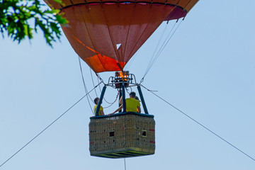 Three people in the hot air balloon nacelle. The balloon is tied to the ground