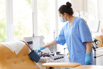 Nurse in uniform checking and preparing medical equipment for blood donation at hospital