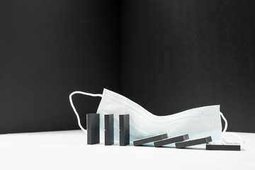 Black Domino is falling and stand on a white background with a medical mask. Concept of business...
