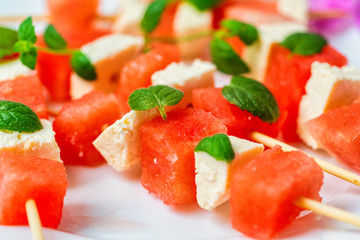 watermelon canapes with cheese sprinkled with mint on a plate