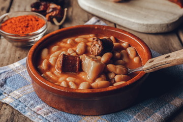 Asturian bean stew on wooden table with some ingredients
