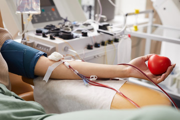 Close-up of female patient with tubes in her arm lying on the couch while donating blood at hospital