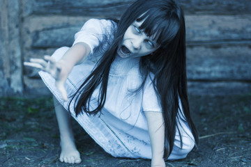 Scary ghost girl pulling with her hand  and crept on the ground