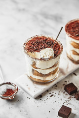 Portion dessert tiramisu in a glass on a marble background
