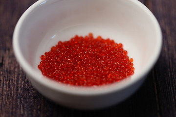 Red beads in white cup on black background