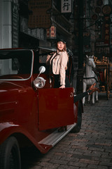 Fototapeta na wymiar a beautiful model poses with vintage red car in the old city