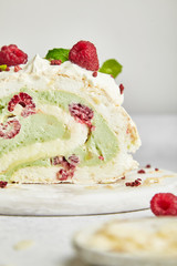 Merengue roll with pistachio cream and raspberry on a bright background