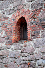 Window of a medieval fortress made of red granite boulders
