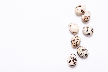 The quail eggs scattered on a white background. Top view