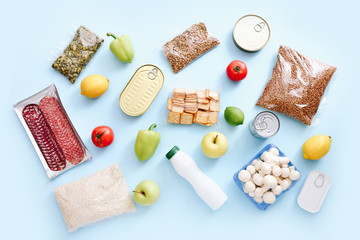 Set of grocery items from canned food, vegetables, cereal on blue background. Food delivery concept. Donation concept. Top view.
