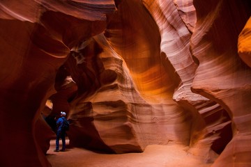 View of the inside of a slot canyon in Page, Arizona. Antelope canyon features sandstone rock formations with erosion lines throughout the walls. A person can be seen which gives perspective.