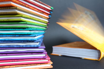 Knowledge - pile of colored magazines with open book on gray background