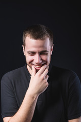 Portrait of an emotional handsome young man, on a black background in the studio, who is gesturing. Expression of emotions and feelings