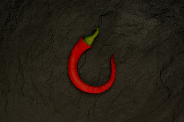 Red hot chili peppers on a black background. Pepper lies on a slate board top view.