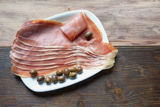 Balkan cuisine . Slices of prsut: dry-cured ham,  Balkan version of prosciutto. Rustic background. Copy space