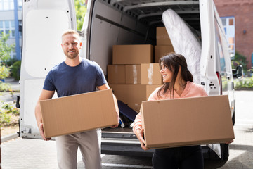 Couple Moving Boxes From Van Or Truck