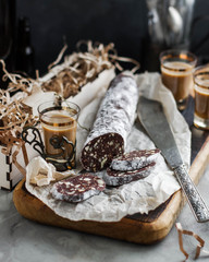 Chocolate salami on a wooden cutting board. Desserts for coffee. Homemade sweet sausage.