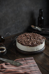 Creamy cheesecake with icing and chocolate chips on a brown table. Piece of pie.