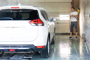 Young man spraying his car clean