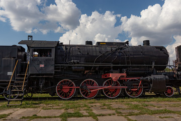 Fototapeta na wymiar vintage steam engine train under sunny blue sky with clouds