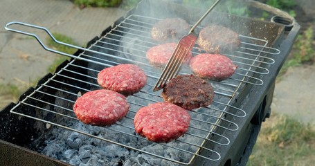 Grilled Meat Cutlets on Metal Grill. Burger patty on grill. Cooking meat for hamburger in coals. Beef or pork cutlet grilling on grid. Roasting minced meat on mangal. Culinary shovel flips cutlets rea