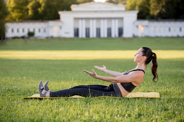Beautiful young woman lying on a yellow mattress doing pilates or yoga, roll up intermediate...