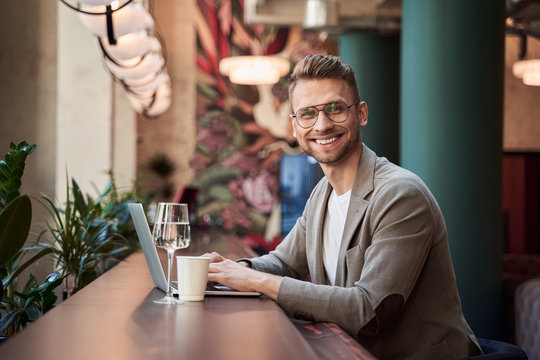 Happy young specialist enjoying distant work with modern gadget