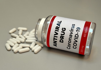 Coronavirus COVID-19 antiviral pills scattered out of the vial. Coronavirus Covid 19 drug for infection treatment against covid19. Healthcare and medical concept.