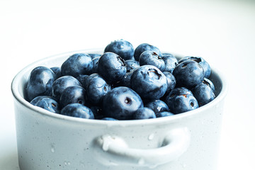 Blueberries in a gray pot on a light gray table. Close-up pot in the center