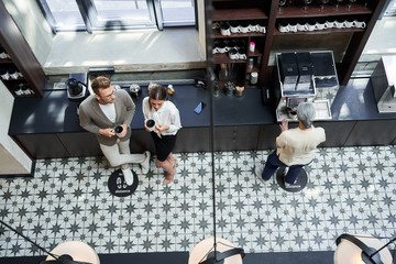 Woman resting with business partner at the office kitchen at the cups of coffee