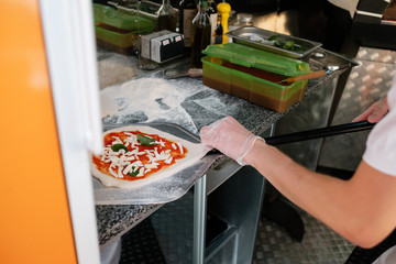 The process of making pizza. The cook prepares the dough for Italian pizza and covers it with tomato paste.