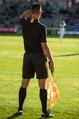 Touchline referee looking against the light during the soccer match.
