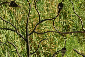 brown metal texture of wrought iron rods in a pattern against a background of green vegetation