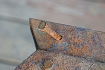 one old long brown rusty bolt on an iron plate outside