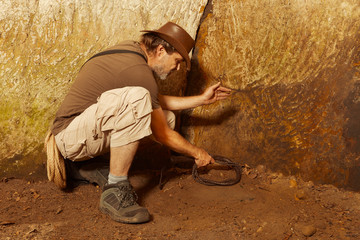 Adventurer in ancient cave on trace of mysterious emerald tablet finding famous artifact