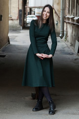 Stylish long-haired Girl in a long green dress is dancing in a shabby alleyway...Typical Petersburg...