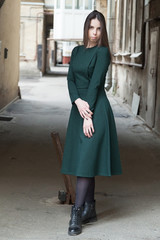 Stylish long-haired Girl in a long green dress is dancing in a shabby alleyway...Typical Petersburg courtyard