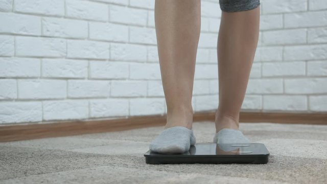 Healthy losing weight. Women's feet stand on the floor scales.