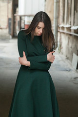 Stylish long-haired Girl in a long green dress freezes in a shabby courtyard...Typical Petersburg...