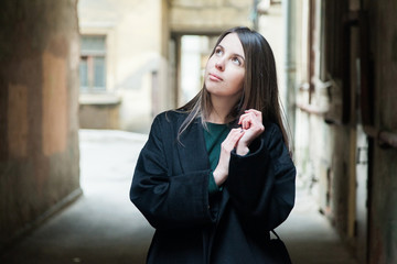 Fototapeta premium Long haired brown eyed girl in black coat portrait in a tyoicalsaint petersburg courtyard