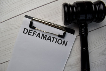 Defamation text write on a paperwork and gavel isolated on office desk.