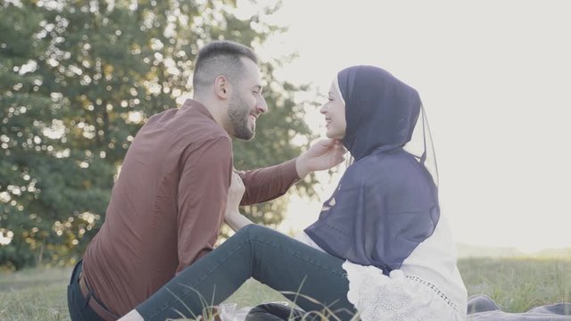 Arabian man stroking his wife who weared in hijab. Love story of mixed couple on nature