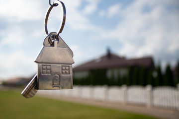 Metal keys to a new house on the background of residential buildings. Concept for buying and renting apartments.