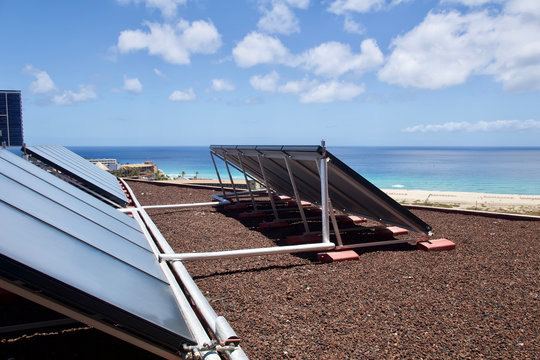 Large solar panels on a beach with a bright cloudy sky
