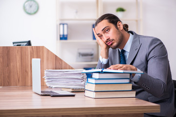 Young male businessman reading books at workplace