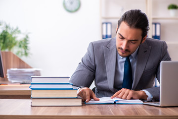 Young male businessman reading books at workplace