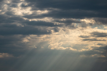 Naklejka na ściany i meble beautiful sun rays shine through the thick heavy cloud in the morning sky after a rain fall