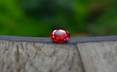 
An oval red gemstone is placed on the floor for jewelry making.