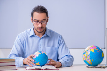 Young male geography teacher in front of whiteboard