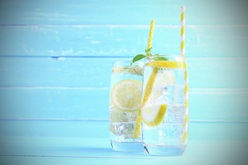 Lemon juice mixing soda no-alcohol with slide lemon and mint in the glass on blue wooden background with copy space. Drinks for healthy this summer.